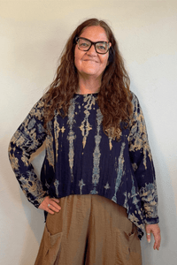 Gertie's 1073Hd Topper in a deep indigo hand-dyed pattern with sage, teal, ochre and muted plum accents, featuring long sleeves, a relaxed silhouette and asymmetrical handkerchief-style hem.
