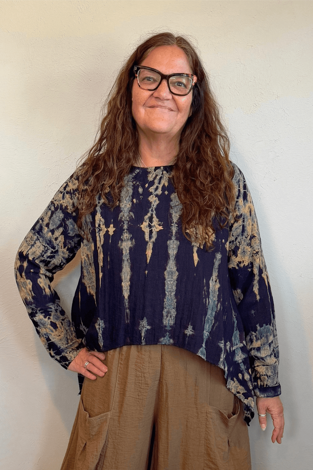 Gertie's 1073Hd Topper in a deep indigo hand-dyed pattern with sage, teal, ochre and muted plum accents, featuring long sleeves, a relaxed silhouette and asymmetrical handkerchief-style hem.