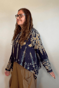 Gertie's 1073Hd Topper in a deep indigo hand-dyed pattern with sage, teal, ochre and muted plum accents, featuring long sleeves, a relaxed silhouette and asymmetrical handkerchief-style hem.