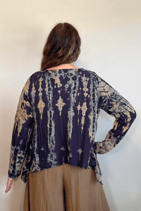 Gertie's 1073Hd Topper in a deep indigo hand-dyed pattern with sage, teal, ochre and muted plum accents, featuring long sleeves, a relaxed silhouette and asymmetrical handkerchief-style hem.