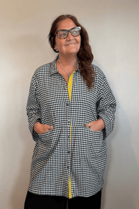 Gertie's 3078C Duster in a small-scale black-and-white check, shown from front, side, and back with an oversized longline silhouette, metal snap front, large patch pockets, and bright yellow contrast trim.