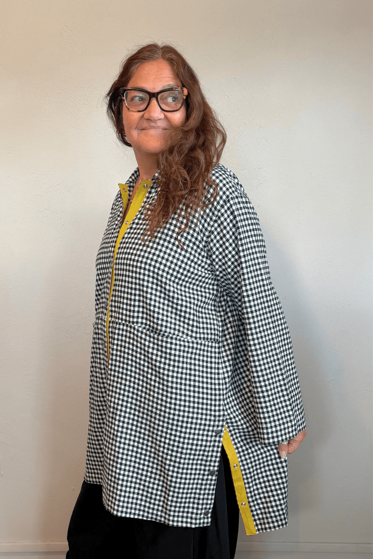 Gertie's 3078C Duster in a small-scale black-and-white check, shown from front, side, and back with an oversized longline silhouette, metal snap front, large patch pockets, and bright yellow contrast trim.