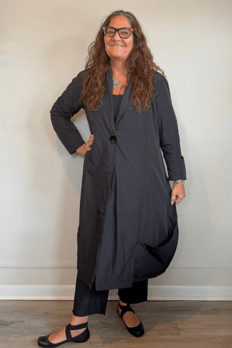 Kozan Aria Jacket in Jet black, a longline jacket with narrow lapels, single-button front, long sleeves, and oversized curved patch pockets.