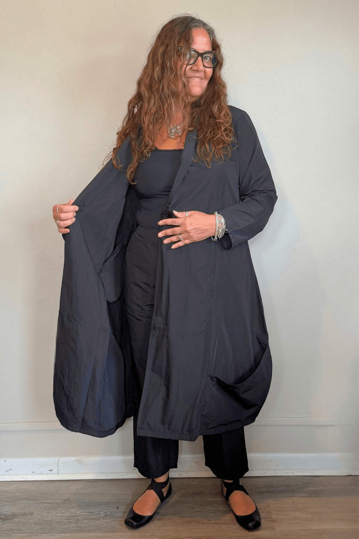 Kozan Aria Jacket in Jet black, a longline jacket with narrow lapels, single-button front, long sleeves, and oversized curved patch pockets.
