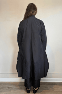 Kozan Aria Jacket in Jet black, a longline jacket with narrow lapels, single-button front, long sleeves, and oversized curved patch pockets.