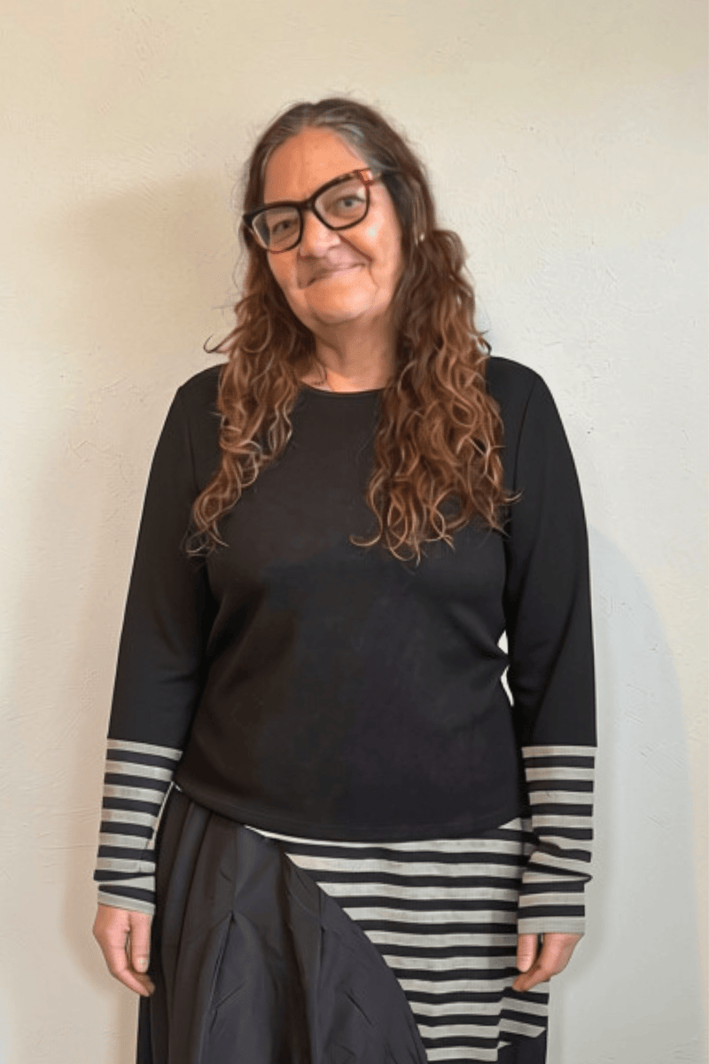 Kozan Merci Tee with a solid black body, round neckline, long sleeves, and extended black-and-gray striped contrast cuffs.