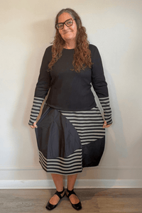 Kozan Merci Tee with a solid black body, round neckline, long sleeves, and extended black-and-gray striped contrast cuffs.
