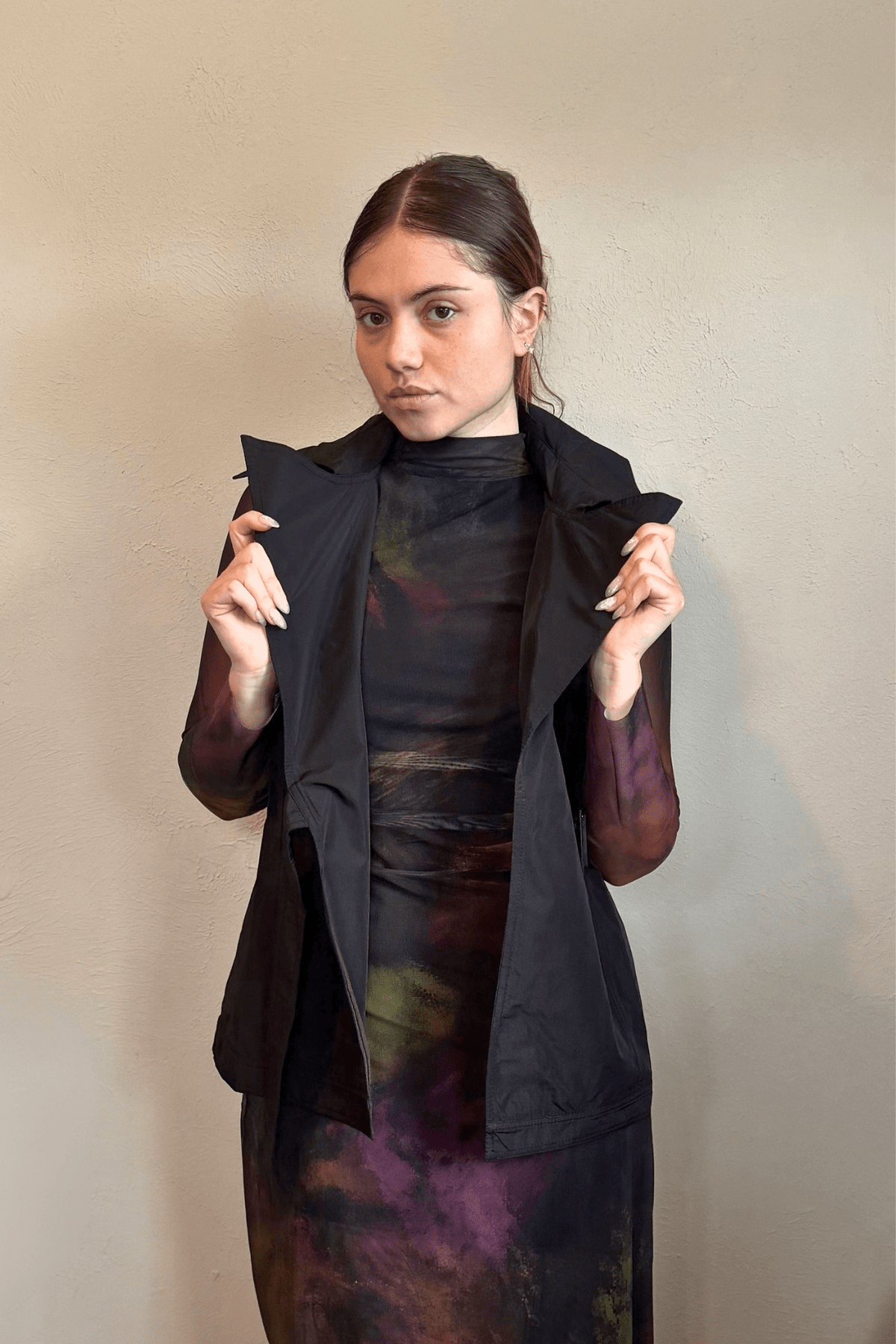 Kozan black A-line sleeveless vest with wide notched lapels, a wrap-style front, and adjustable self-belt with covered rectangular buckle.