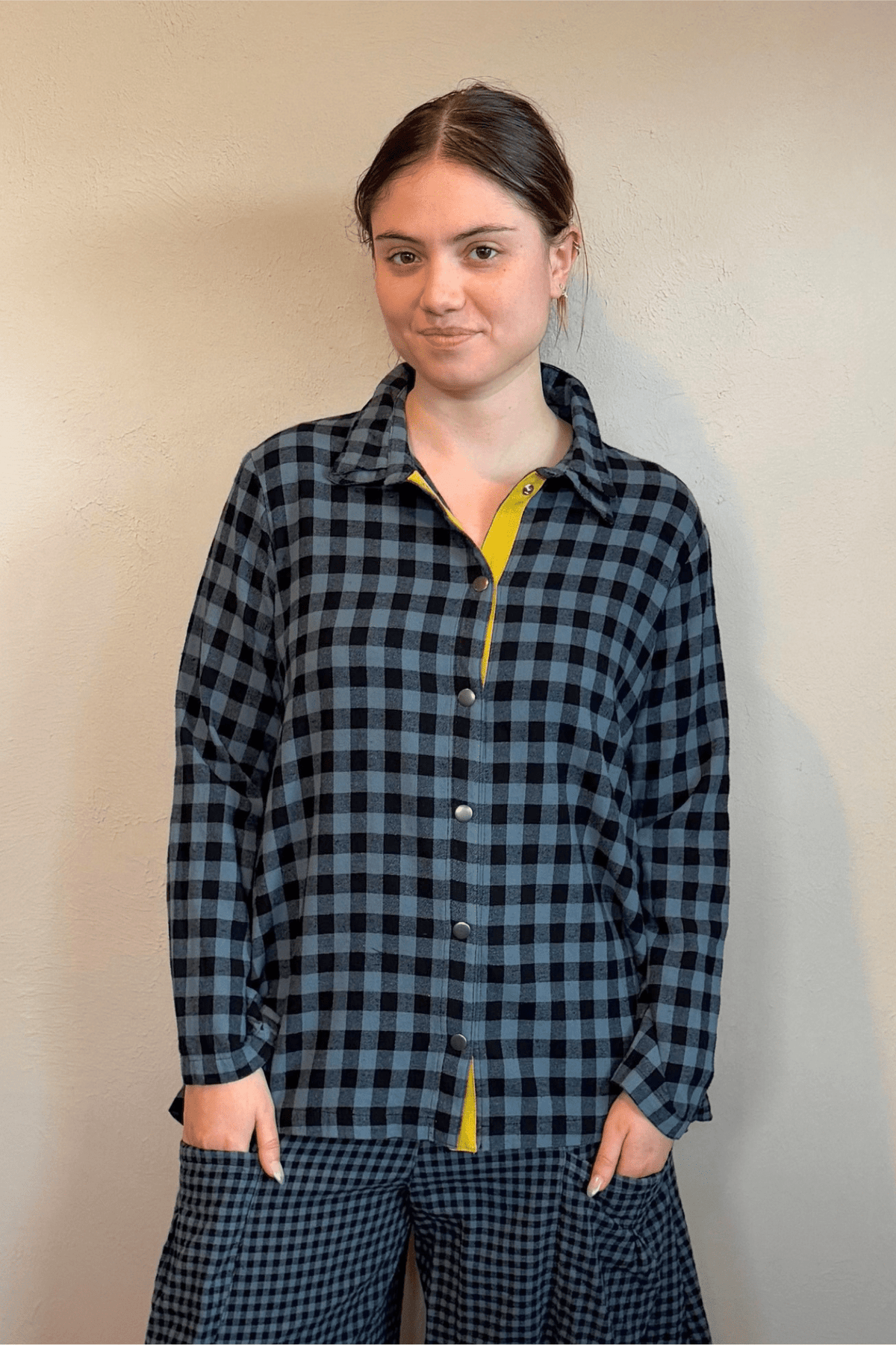 Gertie's 2077B Plackett Gussett Top, a blue-and-black check flannel shirt with long sleeves, metal front snaps, contrasting check side gussets, and yellow placket trim.