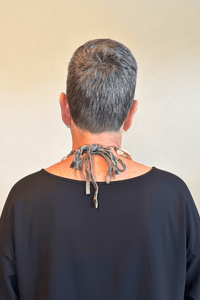 A Rare Bird Painter's Palette Layered Necklace, a wide bib-style statement necklace with layered paint-marked brushes, colorful beads, chains, dangling artist-inspired objects, and long mixed leather fringe ties.