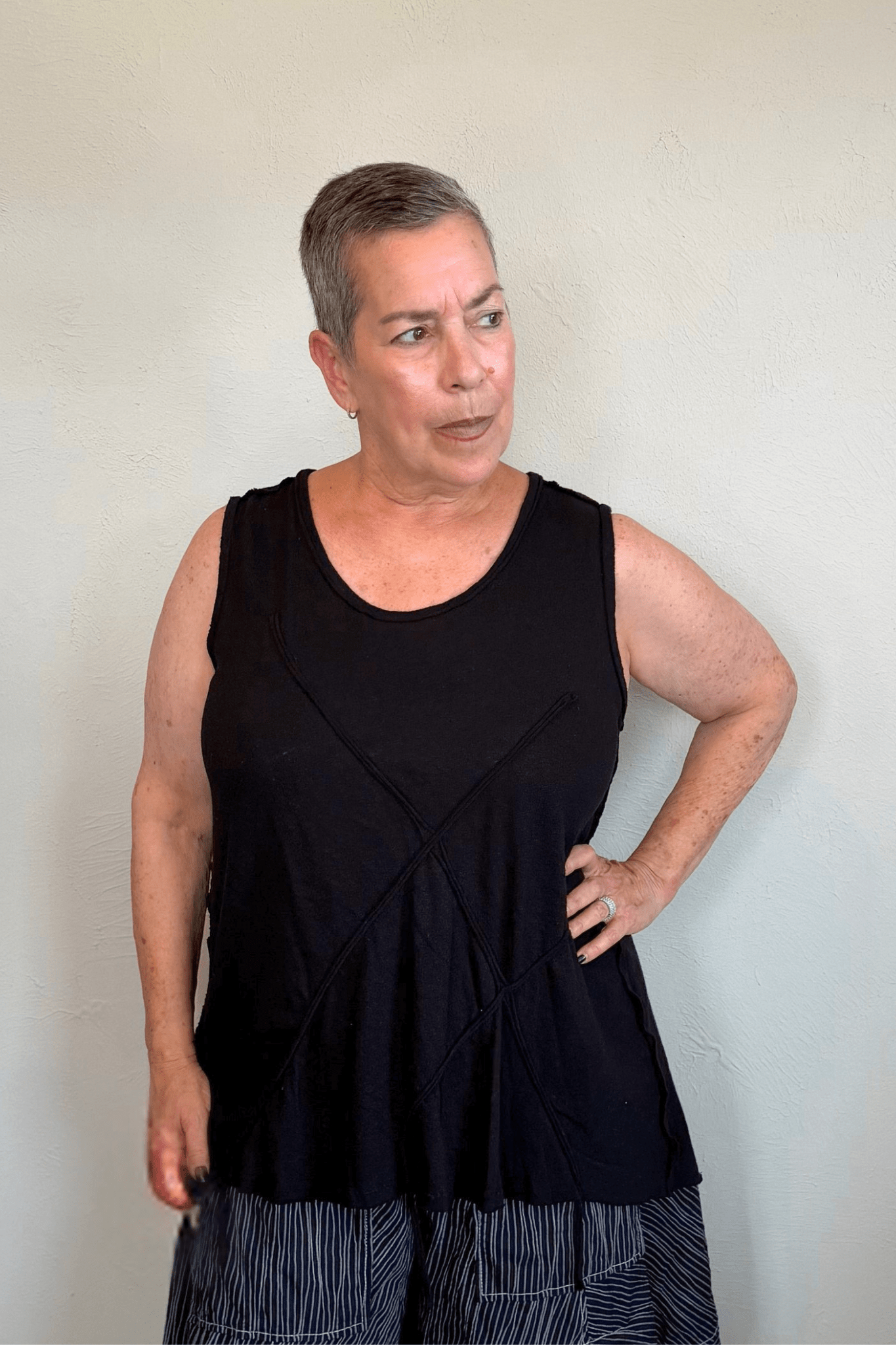 Corded sleeveless tank shown in black and white, with a scoop neckline, relaxed A-line silhouette, abstract raised crisscross cord detailing on the front, softly uneven raw-edge hem, and a clean unembellished back.