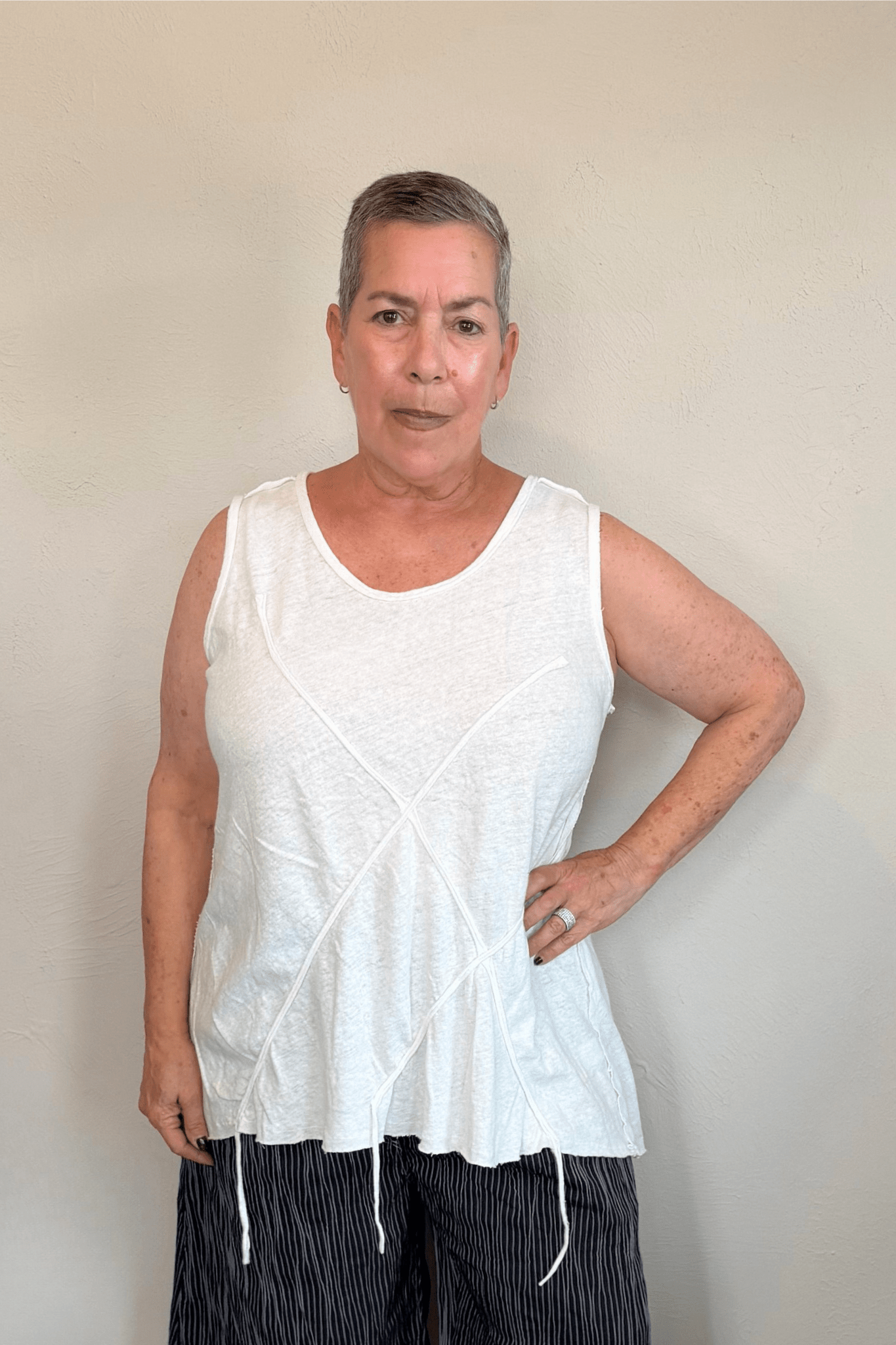 Corded sleeveless tank shown in black and white, with a scoop neckline, relaxed A-line silhouette, abstract raised crisscross cord detailing on the front, softly uneven raw-edge hem, and a clean unembellished back.