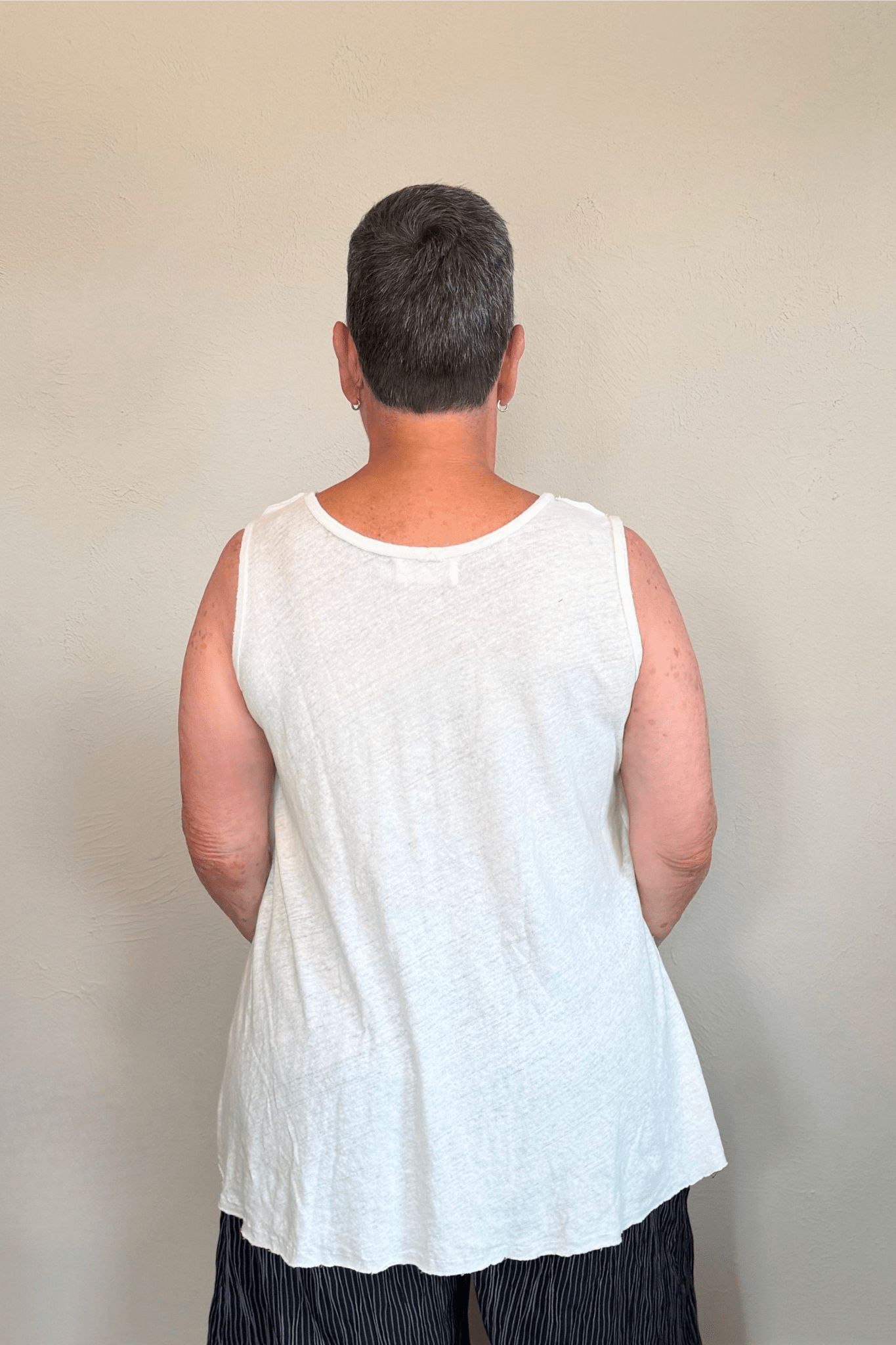 Corded sleeveless tank shown in black and white, with a scoop neckline, relaxed A-line silhouette, abstract raised crisscross cord detailing on the front, softly uneven raw-edge hem, and a clean unembellished back.