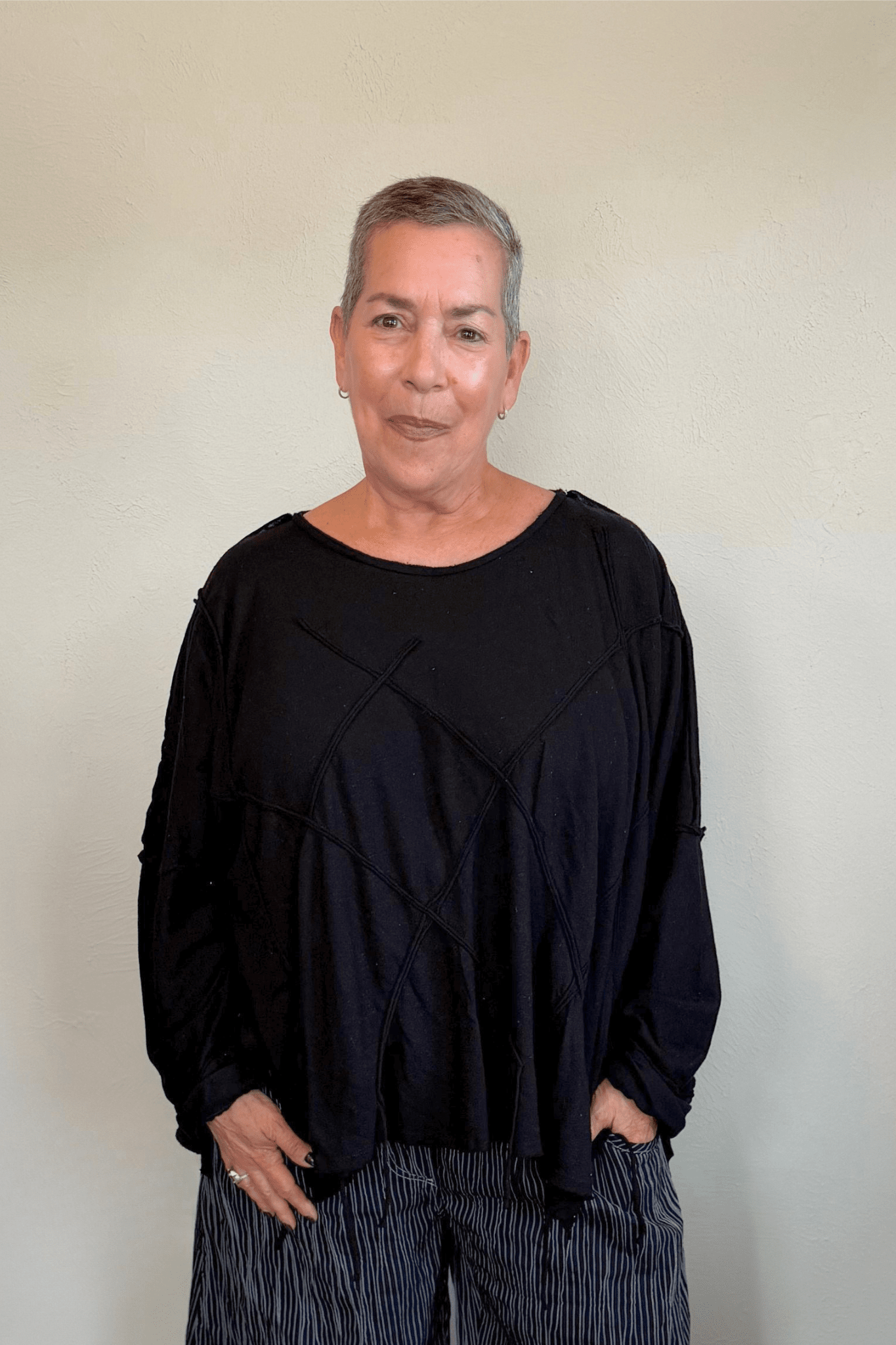 Oversized long-sleeve corded top shown in black and white, with a wide round neckline, dropped shoulders, abstract raised cord detailing across the front, an uneven raw-edge hem, and hanging cord accents.