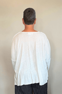 Oversized long-sleeve corded top shown in black and white, with a wide round neckline, dropped shoulders, abstract raised cord detailing across the front, an uneven raw-edge hem, and hanging cord accents.