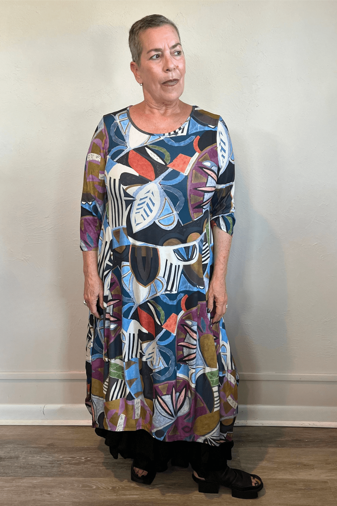 Model wearing the Kozan Demi maxi dress with an allover multicolor abstract print, scoop neckline, three-quarter sleeves, and flowing A-line skirt, shown from front and back.