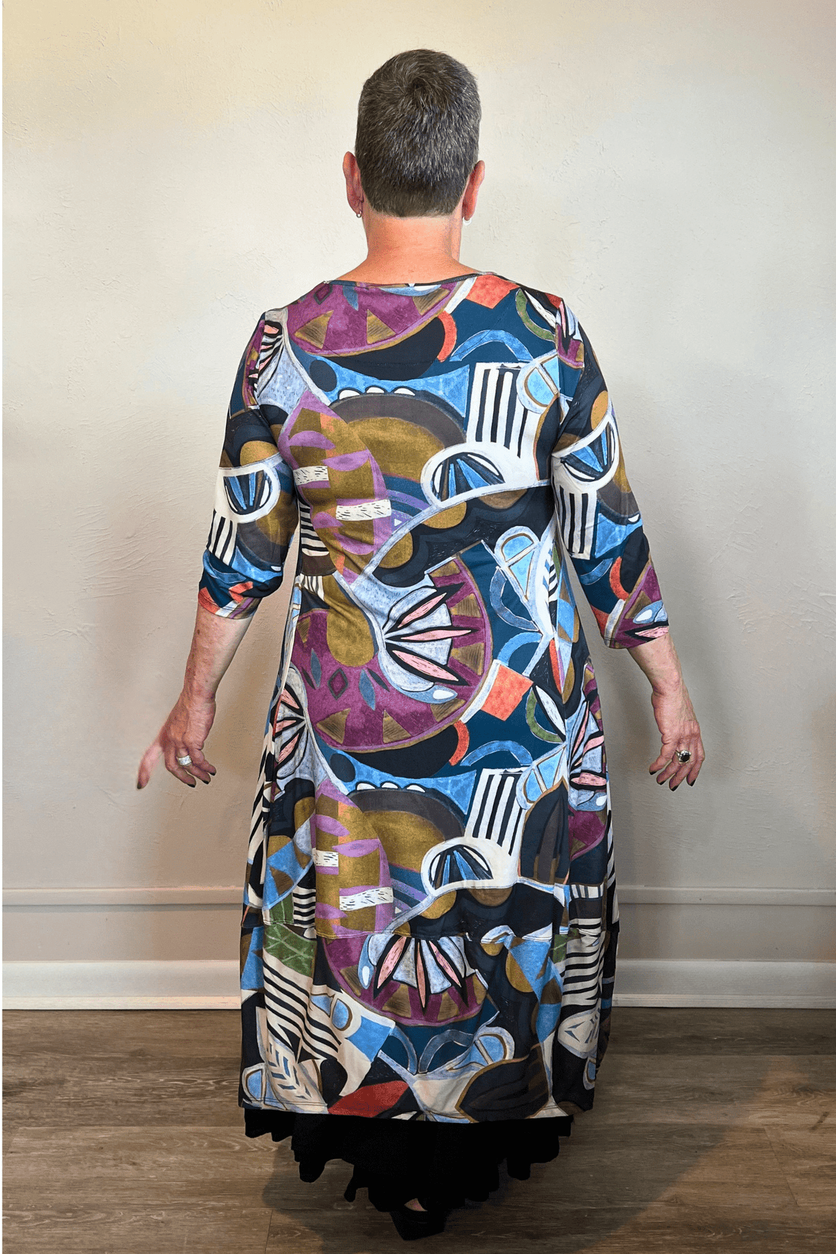 Model wearing the Kozan Demi maxi dress with an allover multicolor abstract print, scoop neckline, three-quarter sleeves, and flowing A-line skirt, shown from front and back.