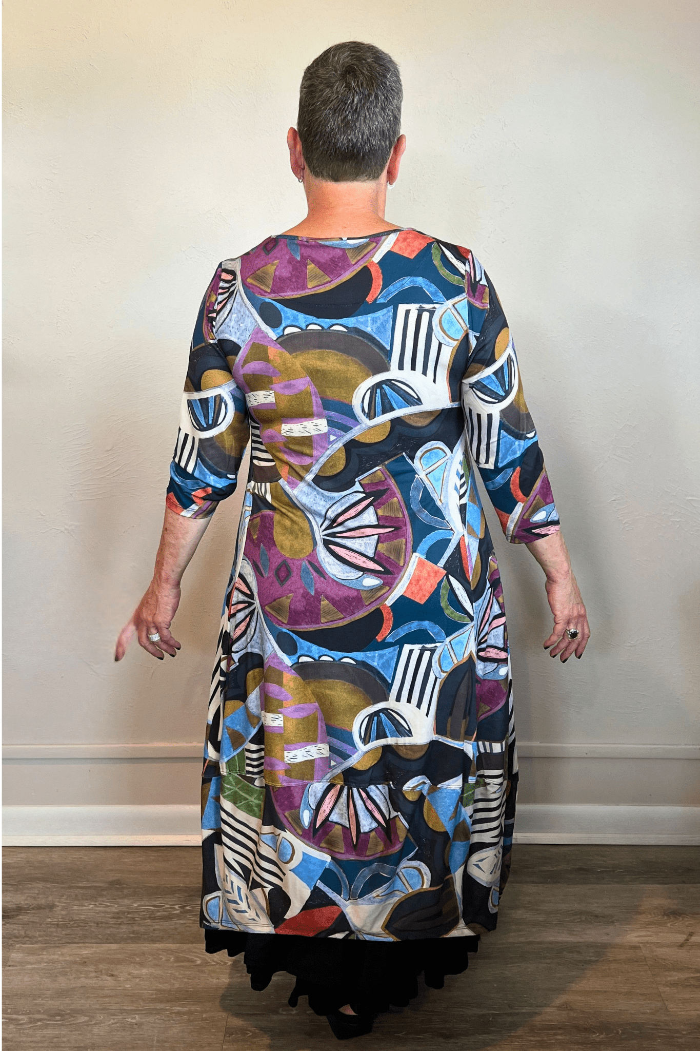 Model wearing the Kozan Demi maxi dress with an allover multicolor abstract print, scoop neckline, three-quarter sleeves, and flowing A-line skirt, shown from front and back.