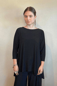 Model wearing the black Kozan Dima tunic with a boat neckline, three-quarter sleeves, and an asymmetrical draped hem, shown from front and back.
