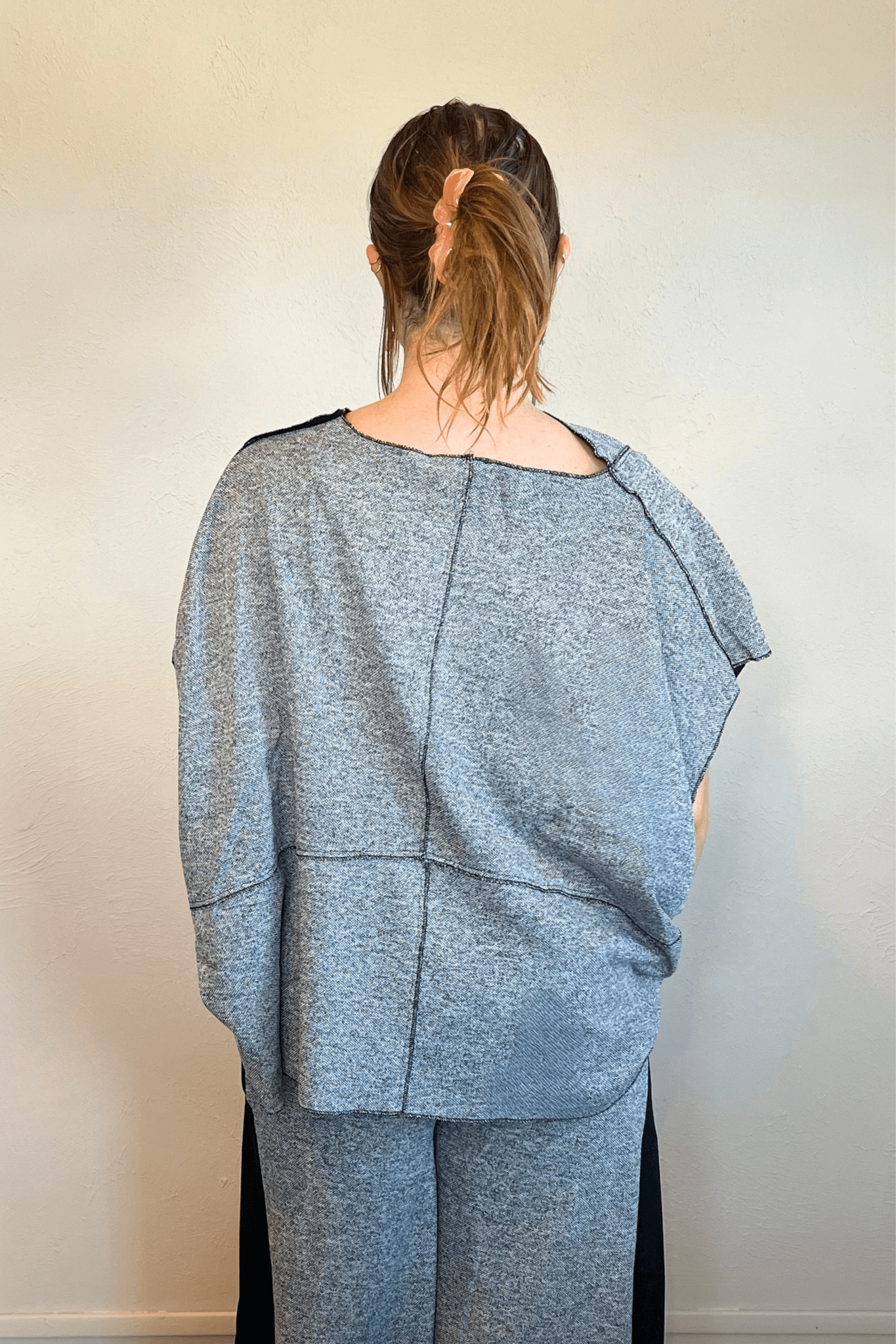 Model wearing the Kozan Fari draped top in heathered gray with black contrast edging, shown from front and back, including a full outfit view with coordinating pants.