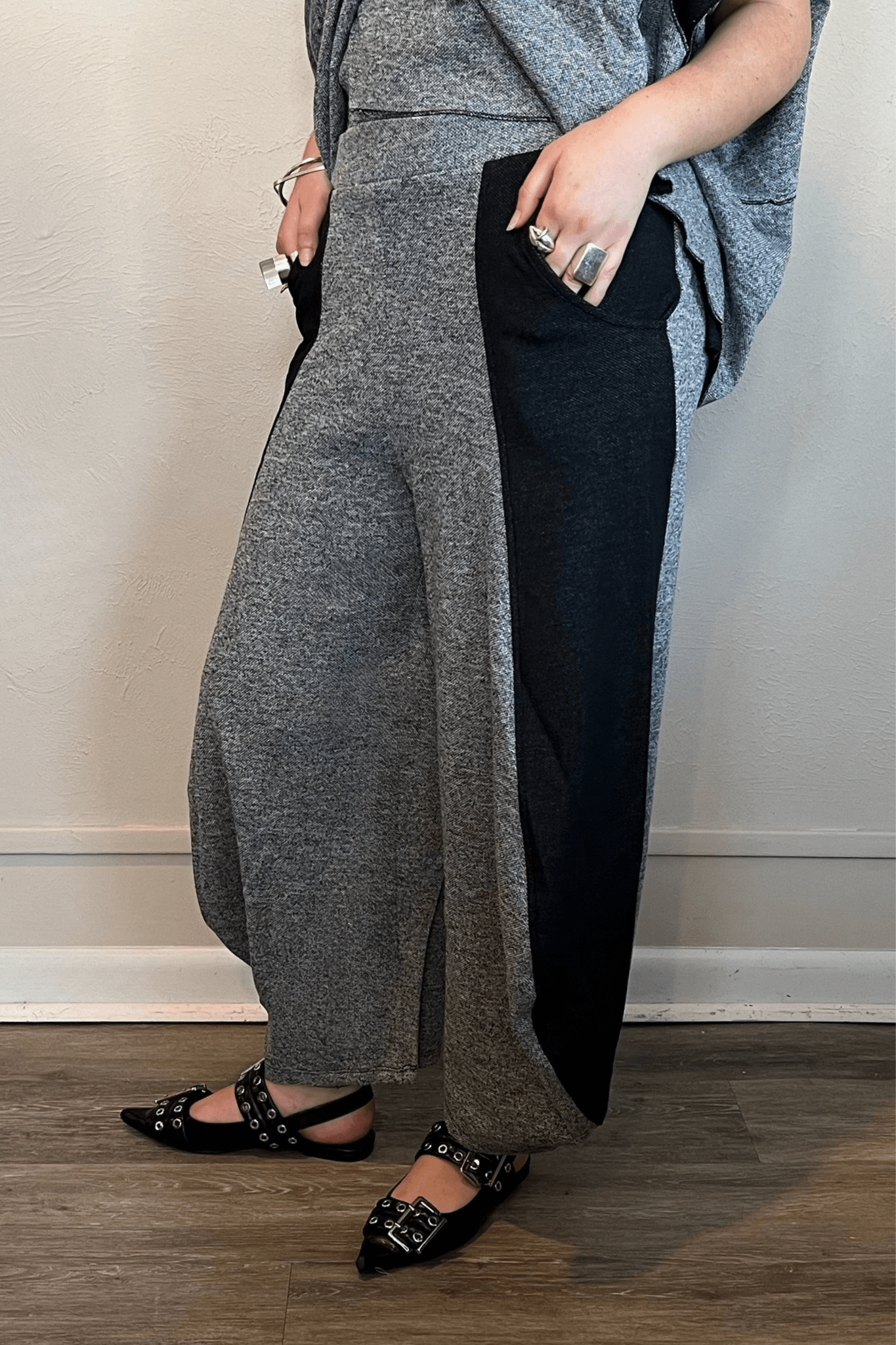 Model wearing the Kozan Jade Pant in heathered gray with black contrast side panels, shown from front, side, and back to highlight the lantern-leg silhouette and curved side pockets.