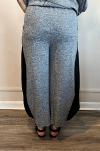 Model wearing the Kozan Jade Pant in heathered gray with black contrast side panels, shown from front, side, and back to highlight the lantern-leg silhouette and curved side pockets.