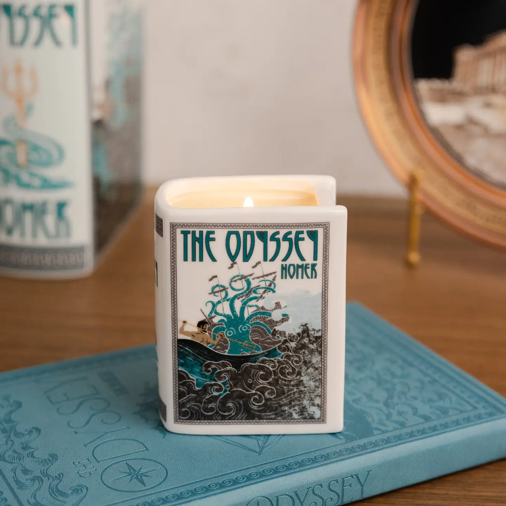 Steel Mill & Co. The Odyssey Book Candle in decorative ceramic book-shaped vessel, showing artwork, sides, and lit candle