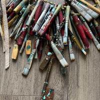 A Rare Bird Painter's Palette Layered Necklace, a wide bib-style statement necklace with layered paint-marked brushes, colorful beads, chains, dangling artist-inspired objects, and long mixed leather fringe ties.