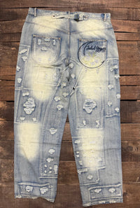Jaded Gypsy Denim Peace And Love Jeans with distressed patchwork details, faded blue wash, embroidered back design, and rolled cuffs