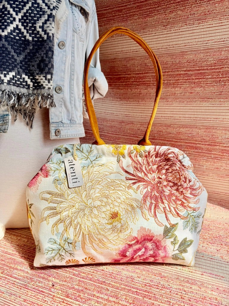 Atenti Primrose Molly handbag with oversized floral print, caramel-colored double handles and base, and structured snap-frame silhouette