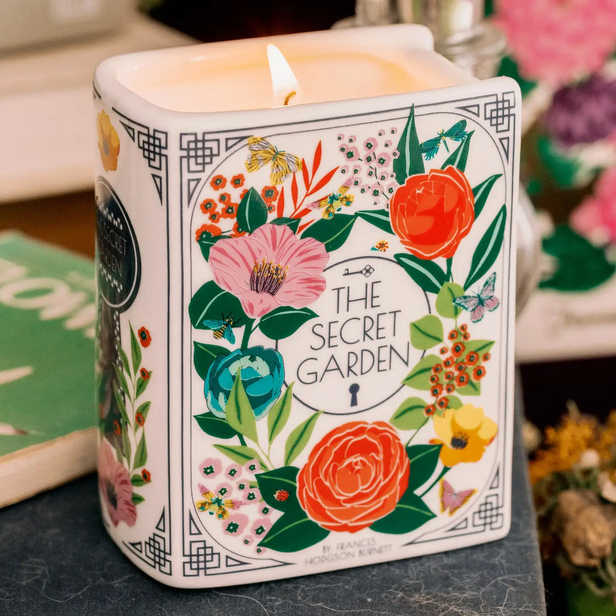 Steel Mill & Co. The Secret Garden Book Candle featuring colorful botanical illustrations in a ceramic book-shaped vessel