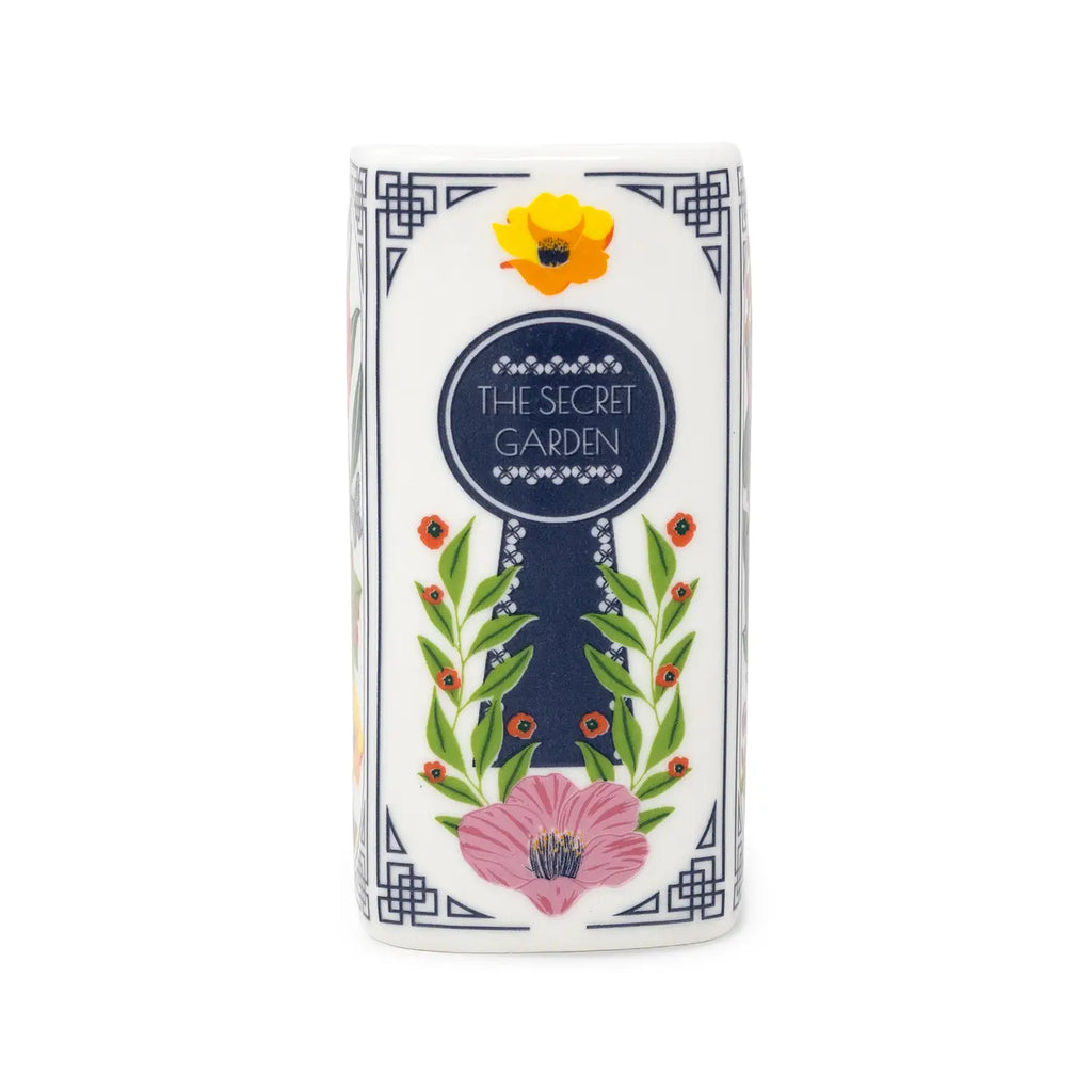 Steel Mill & Co. The Secret Garden Book Candle featuring colorful botanical illustrations in a ceramic book-shaped vessel