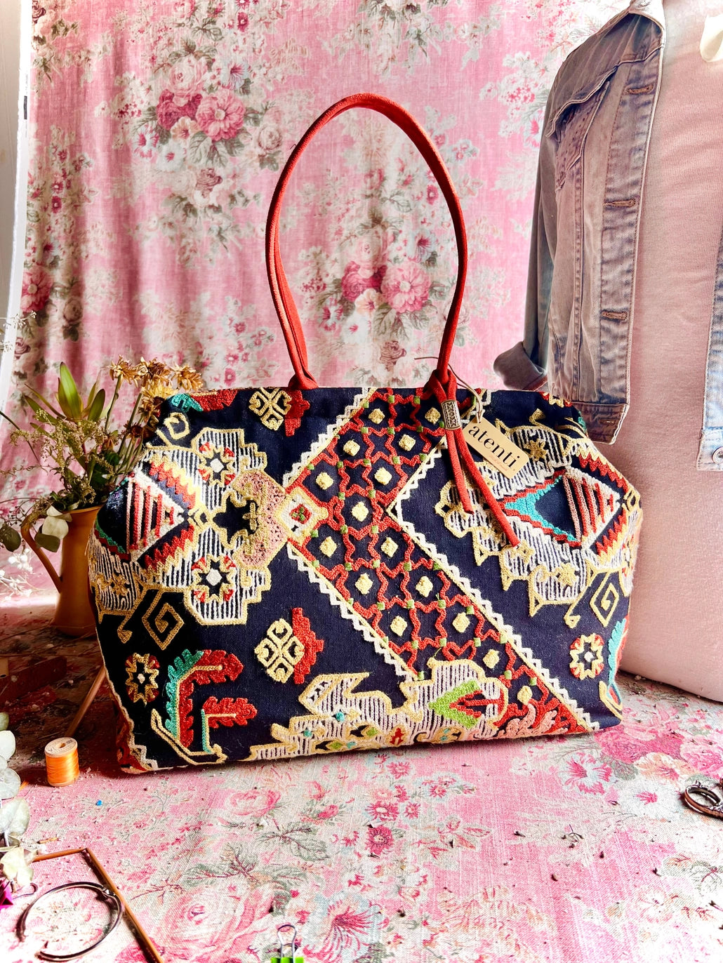 Atenti Sew Crewel Pioneer handbag with multicolor crewel-style embroidery, bright red double handles, and structured snap-frame silhouette