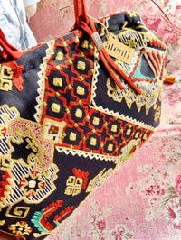 Atenti Sew Crewel Pioneer handbag with multicolor crewel-style embroidery, bright red double handles, and structured snap-frame silhouette