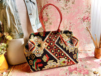 Atenti Sew Crewel Pioneer handbag with multicolor crewel-style embroidery, bright red double handles, and structured snap-frame silhouette